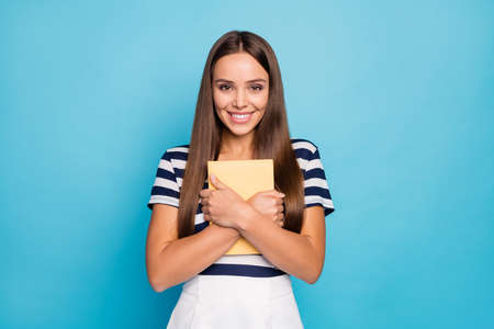 Photo of beautiful pretty charming lady hold hands close to chest personal diary write secrets adorable wear striped t-shirt white skirt isolated blue color backgroundの写真素材