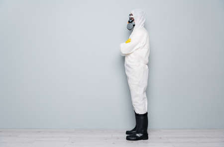 Full body profile photo of professional guy disinfectant watch public places disinfection arms crossed wear hazmat protective suit goggles mask gloves boots isolated grey color backgroundの写真素材