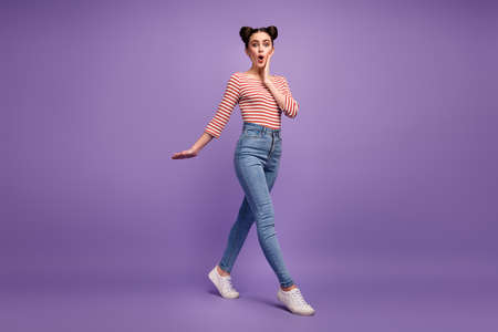 Full body profile photo of pretty teen lady hand on cheek walk shopping center black friday wear white red casual striped shirt jeans shoes isolated purple pastel color backgroundの写真素材