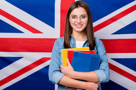 Close-up portrait of her she nice attractive smart clever cheerful cheery girl holding in hands exercise book lesson classes courses isolated over british stripes flag backgroundの写真素材