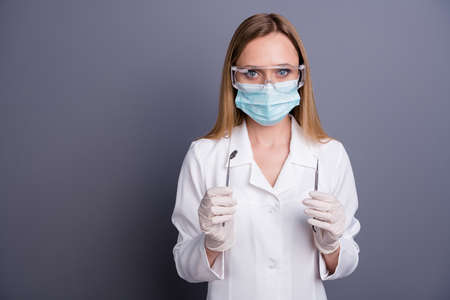 Portrait of nice attractive blonde girl experienced doc holding in hands tools equipment stomatology ambulance assistance 24 7 clinic isolated over grey violet pastel color backgroundの写真素材