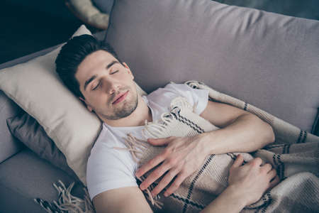 Close-up portrait of his he nice attractive calm peaceful tranquil sleepy virile brunette guy lying on divan resting sleeping in living-room indoorsの写真素材