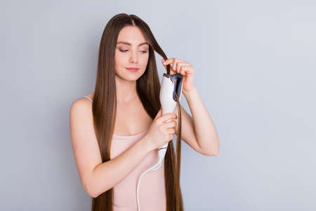 Photo of beautiful model lady long hairstyle hold electric styler curler making straight curls wavy...
