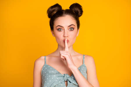 Portrait of amazed serious girl hear incredible secret novelty ask dont share rumor put finger mouth wear style stylish trendy singlet isolated over shine color backgroundの写真素材