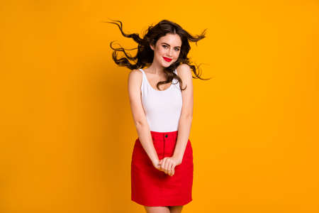 Photo of funny pretty lady hairdo flight satisfied look enjoy warm summer, breeze flirty mood wear white casual tank-top red short skirt isolated yellow bright color backgroundの写真素材