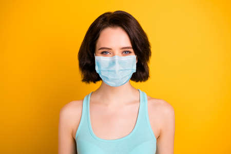 Close up photo of beautiful charming confident girl stay home covid-19 quarantine wear fabric mask isolated with yellow vivid backgroundの写真素材