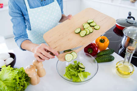 Cropped close-up view of her she nice girl housewife housemaid, cooking lunch dinner dish snack chopping knife on wooden board over table desk in modern light white interior kitchen houseの写真素材