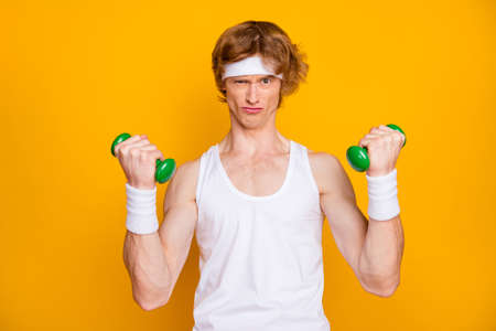 Close-up portrait of his he nice attractive focused motivated guy doing work out with small light dumbbell self developing endurance isolated over bright vivid shine vibrant yellow color backgroundの写真素材