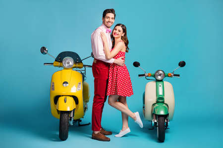 Full body photo of gentle tender spouses man woman have honeymoon vacation ride drive motor bike hug embrace cuddle wear shirt pants isolated over blue color backgroundの写真素材