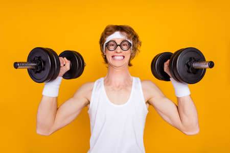 Close-up portrait of his he nice attractive funky cheerful cheery motivated guy sportsman lifting barbell doing good work out isolated over bright vivid shine vibrant yellow color backgroundの写真素材