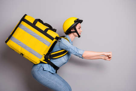 Profile side photo positive girl courier drive imaginary motor cycle bike hold thermal backpack deliver customer package lunch wear denim jeans shirt helmet isolated gray color backgroundの写真素材