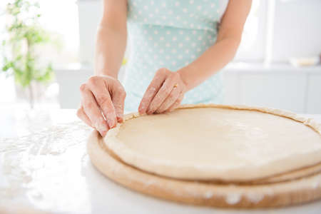 Cropped close up photo of concentrated girl want prepare margarita pizza make crust dough chopping wooden board in modern kitchenの写真素材