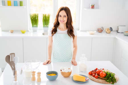 Photo of beautiful housewife chef enjoy morning cooking tasty dinner family recording video for blog quarantine stay home wear apron stand modern kitchen indoorsの写真素材