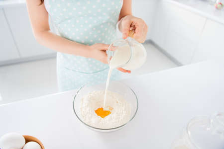 Cropped photo of housewife early morning weekend preparing cookies for family children husband making dough pouring adding milk modern kitchen indoors casual clothingの写真素材