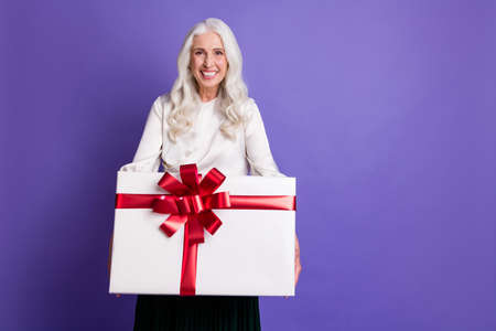 Portrait of candid funky old woman grandparent receive dream present hold big gift box package feel content wear good look outfit isolated over purple color backgroundの写真素材