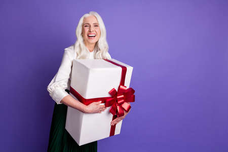 Portrait of content funky candid old woman granny hold big present box she always dream get family 8-march start laugh wear good look clothes isolated over vivid color backgroundの写真素材