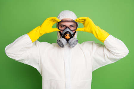 Close-up portrait of his he nice confident content professional disinfectant putting gas mask equipment on anti disease sickness illness service isolated over green pastel color backgroundの写真素材