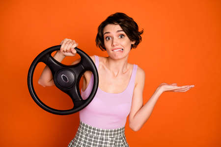 Portrait of frustrated girl hold steering wheel have no drive license get car crash bite lips teeth wear tank-top checkered plaid isolated over bright shine color backgroundの写真素材