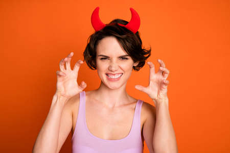 Portrait of sly naughty girl imagine she aggressive devil hold fingers claws roar wear horns headband stylish trendy singlet isolated over shine color backgroundの写真素材