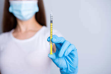 Closeup cropped photo of young lady doctor hospital examination clinic hold syringe dose patient vaccine injection treatment wear protect face mask isolated grey color backgroundの写真素材