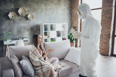 Photo of two people patient lady sit sofa unwell call ambulance guy doc virologist collected saliva probe listen questions how to take pills wear uniform protection visit her flat indoorsの写真素材