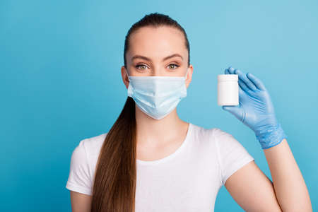 Closeup photo of beautiful lady hold showing bottle painkillers capsule pills swiss vitamins good mood patient wear latex gloves protect face mask t-shirt isolated blue color backgroundの写真素材