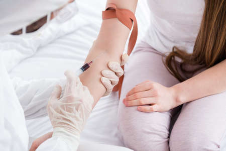 Closeup photo of patient lady guy doc make injection collecting probe vein blood covid antibodies research vaccine elastic harness on hand wear uniform suit protection bedroom indoorsの写真素材
