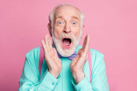 Closeup photo of excited crazy attractive grandpa open mouth listen good news astonished facial expression wear mint shirt suspenders bow tie isolated pink pastel backgroundの写真素材