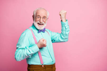 Profile photo of funky crazy grandpa raise fists ecstatic good mood cool achievement wear specs mint shirt suspenders violet bow tie trousers isolated pink pastel color backgroundの写真素材