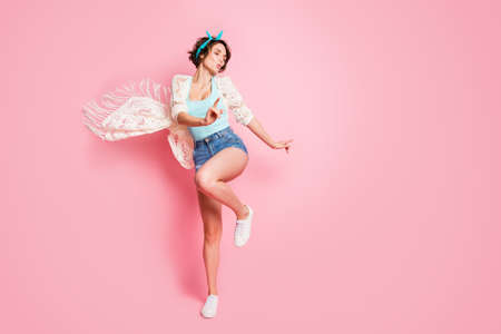 Full size photo of attractive lady rejoicing summer student party dance moving excited wear headband lace cloak singlet denim shorts footwear isolated pastel pink color backgroundの写真素材