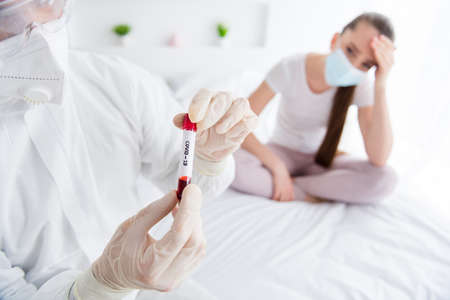 Closeup photo of patient student lady unwell emergency doc virologist collected blood probe flask flu cold covid symptom check tube wear mask gloves protective uniform bedroom indoorsの写真素材