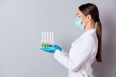 Profile photo of virologist doc lady experienced professional hold test tubes examining vaccine probes wear gloves facial mask protective glasses uniform lab coat isolated grey backgroundの写真素材