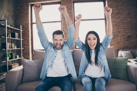 Portrait of nice attractive overjoyed ecstatic cheerful friends friendship sitting on divan playing videogame celebrating contest win winner at modern brick loft industrial interior house flatの写真素材