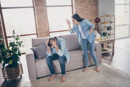 Full length photo of outraged woman shout man did mistake fail feel despair touch hands head sit cozy comfort leisure divan in house indoorsの写真素材