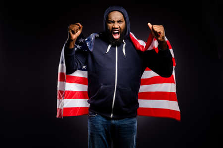 Photo of crazy afro american guy hold us flag encourage solidarity human rights revolt scream wear fashion sweater jumper isolated over black color backgroundの写真素材