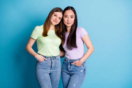 Photo of cheerful two people ladies lesbians couple hugging good mood young students best friends buddies positive emotions wear casual t-shirts jeans isolated blue color backgroundの写真素材
