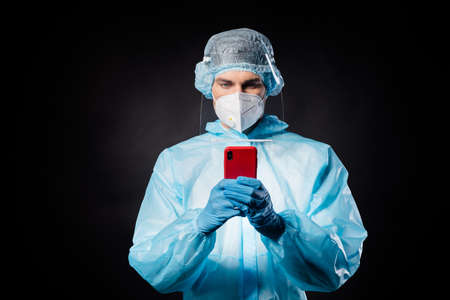 Photo of guy doc virologist hold telephone hands chatting patients online wear gloves respirator...