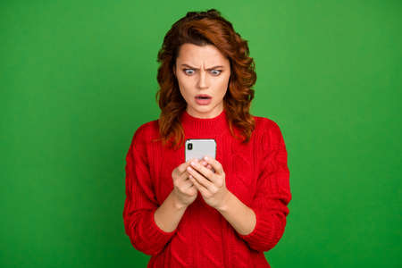 Portrait of astonished woman use cell phone read social network comments post impressed scream omg unbelievable wear knitted pullover isolated over bright color backgroundの写真素材