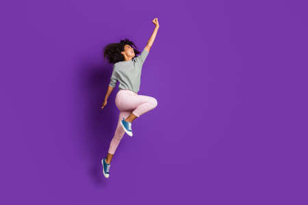Full length photo of crazy funny afro american girl jump hold hand try catch parasol wear casual style pink outfit isolated over purple color backgroundの写真素材