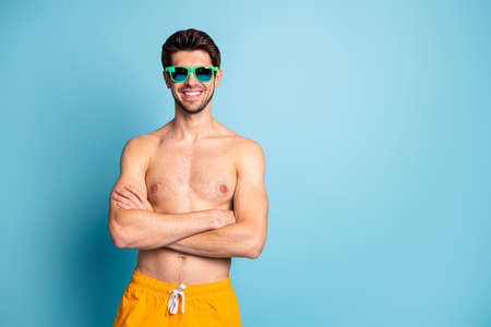 Photo of cheerful positive toothy beaming man standing with arms crossed near empty space isolated pastel blue color backgroundの写真素材
