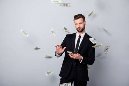 Portrait of cool luxury man entrepreneur manager win lottery cashback throw waste money dollars falling flying wear black blazer tie pants isolated over grey color backgroundの写真素材