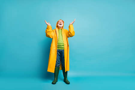 Full length body size view of his he nice cheerful cheery positive glad grey-haired man wearing, yellow topcoat expecting rain drop isolated over bright vivid shine vibrant blue color backgroundの写真素材