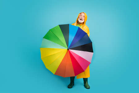 Full length body size view of his he nice cheerful cheery friendly grey-haired man wearing yellow topcoat spinning colorful parasol isolated over bright vivid shine vibrant blue color backgroundの写真素材