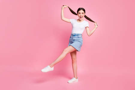 Full length profile photo of pretty lady walking down street enjoy sunny day weather wear casual white t-shirt mini denim skirt shoes isolated pastel pink color backgroundの写真素材