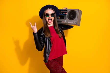 Portrait of her she nice attractive cool crazy comic fashionable cheerful cheery straight-haired girl carrying boombox showing horn sign isolated on bright vivid shine vibrant yellow color backgroundの写真素材