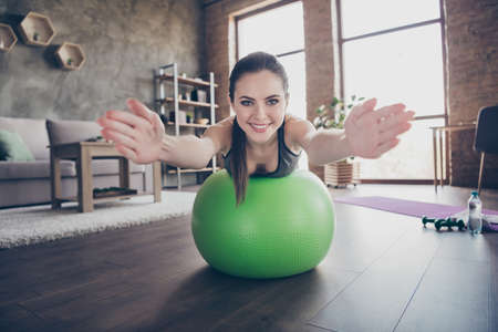 Photo of beautiful lady quarantine hobby training stay home dynamic pilates stretching practicing house lying on fit ball do exercises for abdomen muscles raise arms living room indoorsの写真素材
