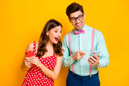 Photo of pretty lady handsome guy direct telephone finger show funny picture blogger users wear red dotted dress shirt bowtie isolated yellow bright color backgroundの写真素材