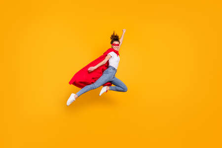 Full length body size view of her she nice attractive lovely strong powerful fit slim cheerful girl jumping wearing mantle flying fast isolated on bright vivid shine vibrant yellow color backgroundの写真素材