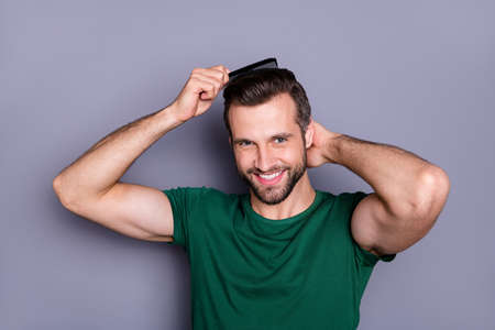 Portrait of positive guy comb haircut after spa salon procedure wash enjoy haircare therapy wear green t-shirt isolated over gray color backgroundの写真素材