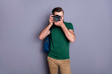 Portrait of concentrated guy enjoy travel weekend use professional camera shooting picture wear green pants isolated over gray color backgroundの写真素材